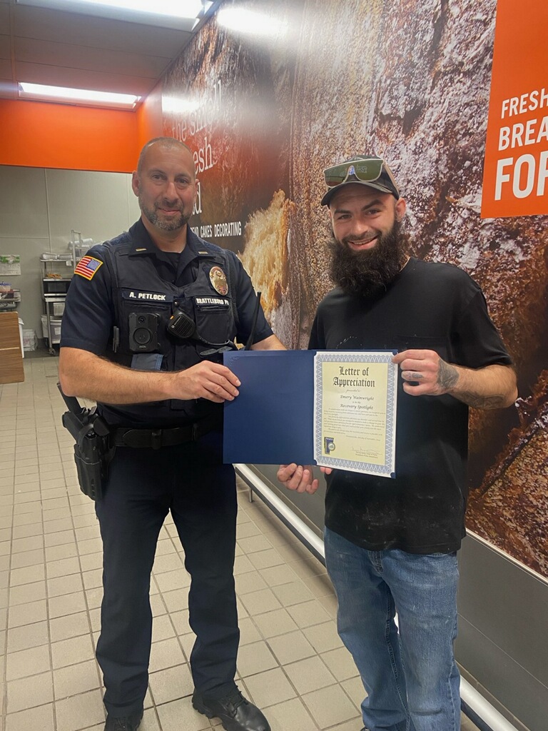 An image of Captain Adam Petlock presenting an award of appreciation to Emery Wainwright.