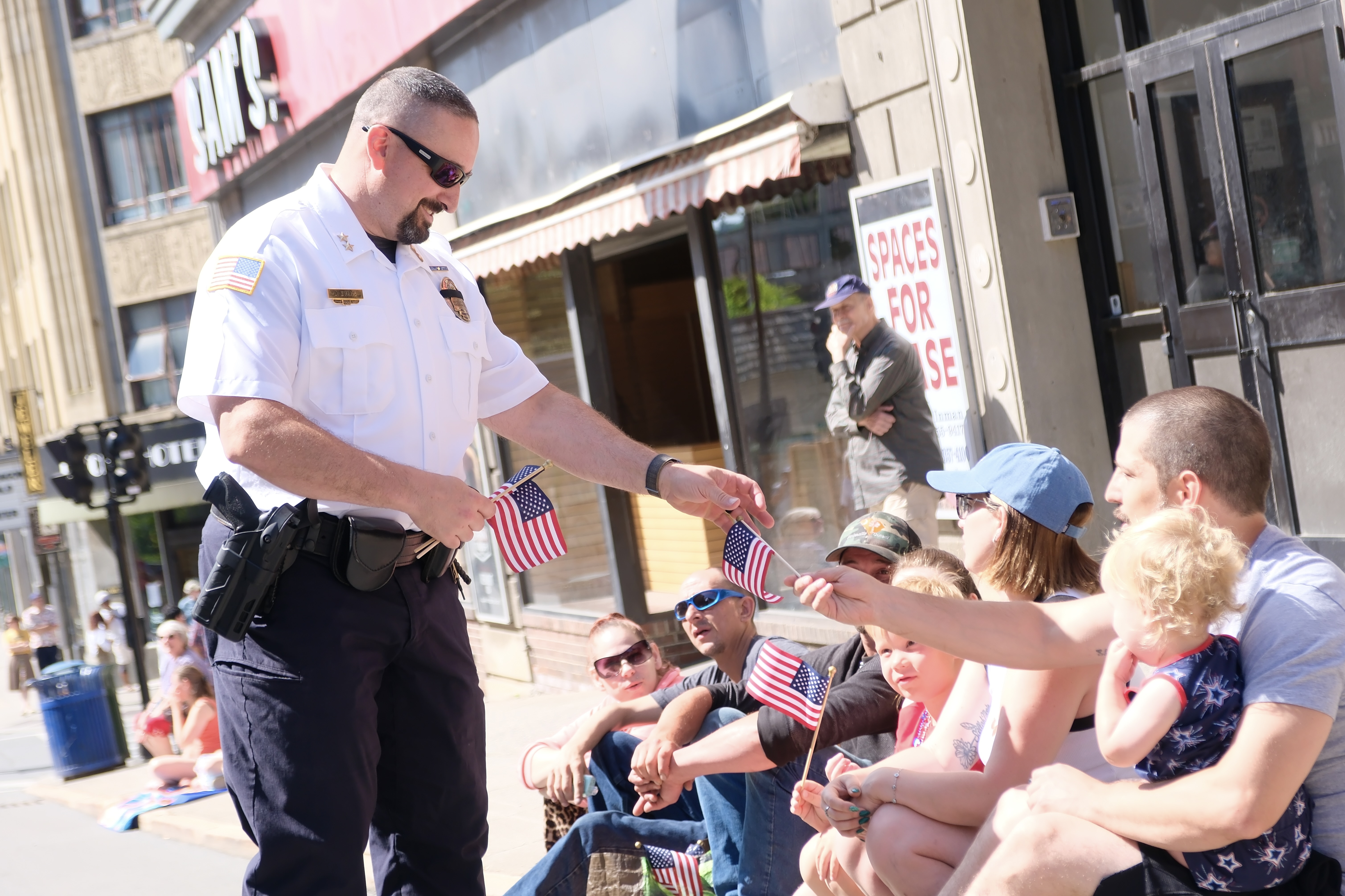 A photo of Chief Jeremy Evans handing an American flag to onlookers during the Brattleboro Goes Fourth parade in 2025.