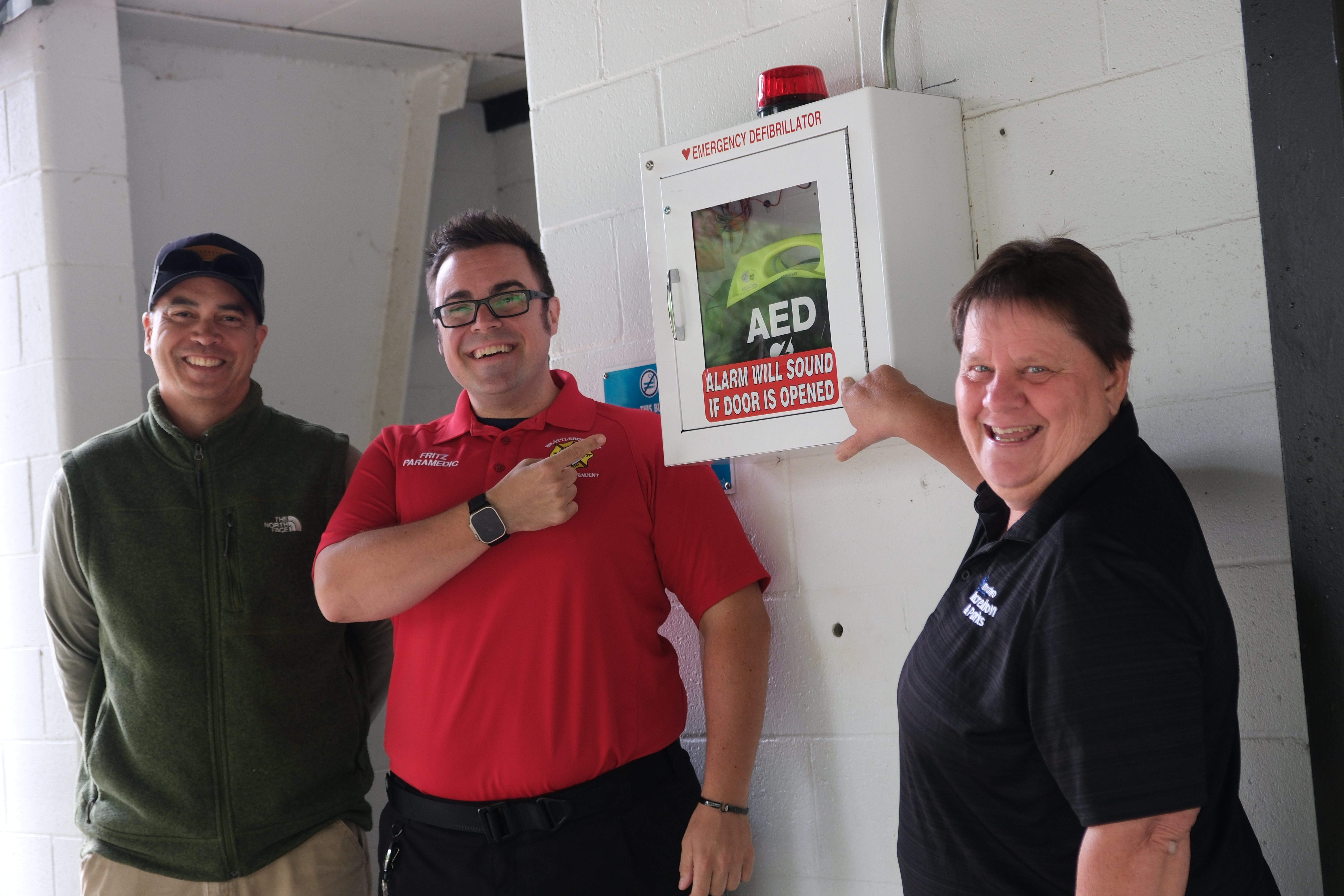 A photo of Town staff standing next to the new AED installed outside the skating rink at Living Memorial Park.
