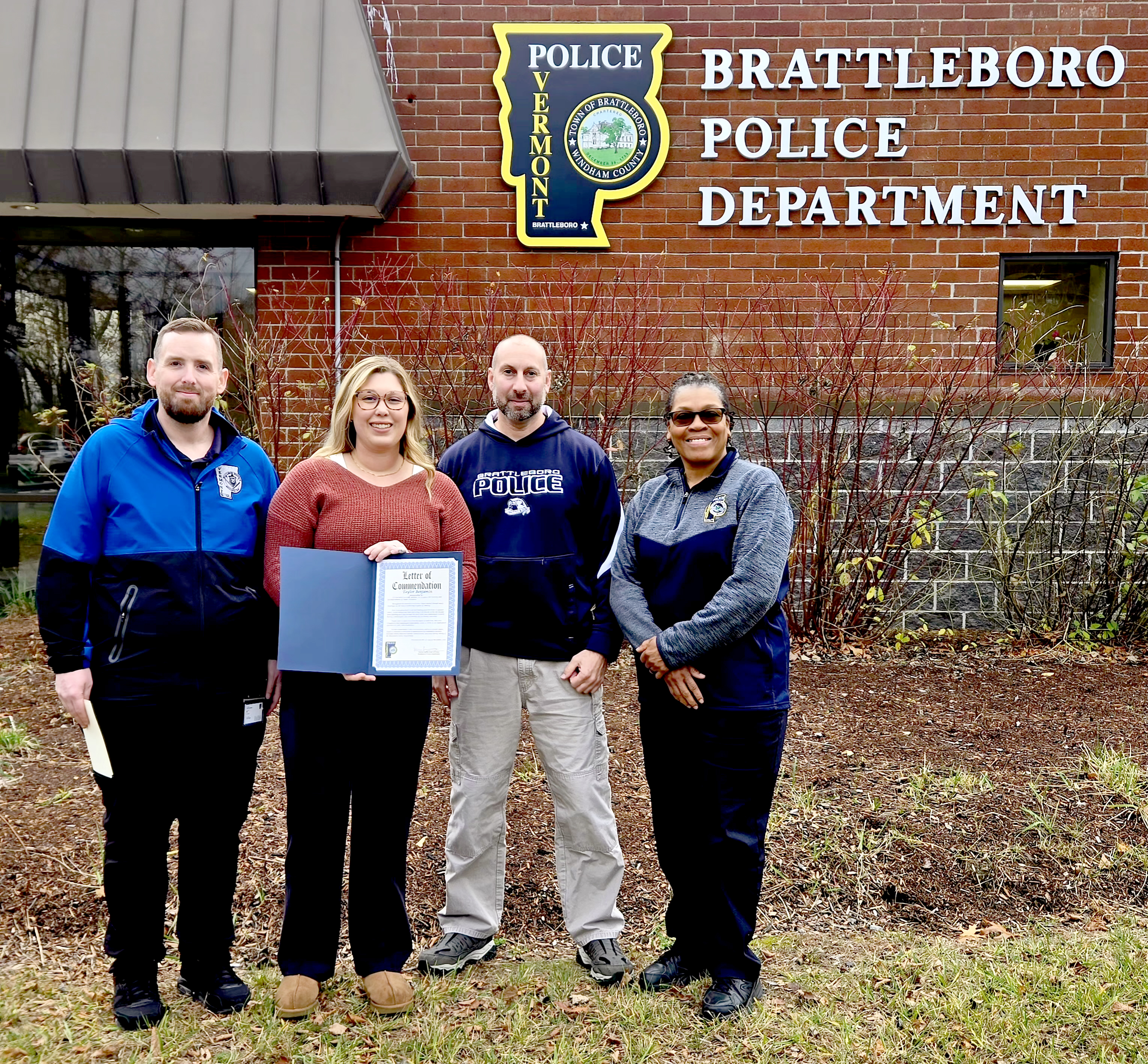 A photo of Taylor Benjamin receiving a certificate of appreciation from Community Resource Specialist Justin Johnston, Captain Adam Petlock, and Chief Norma Hardy of the Brattleboro Police Department. 